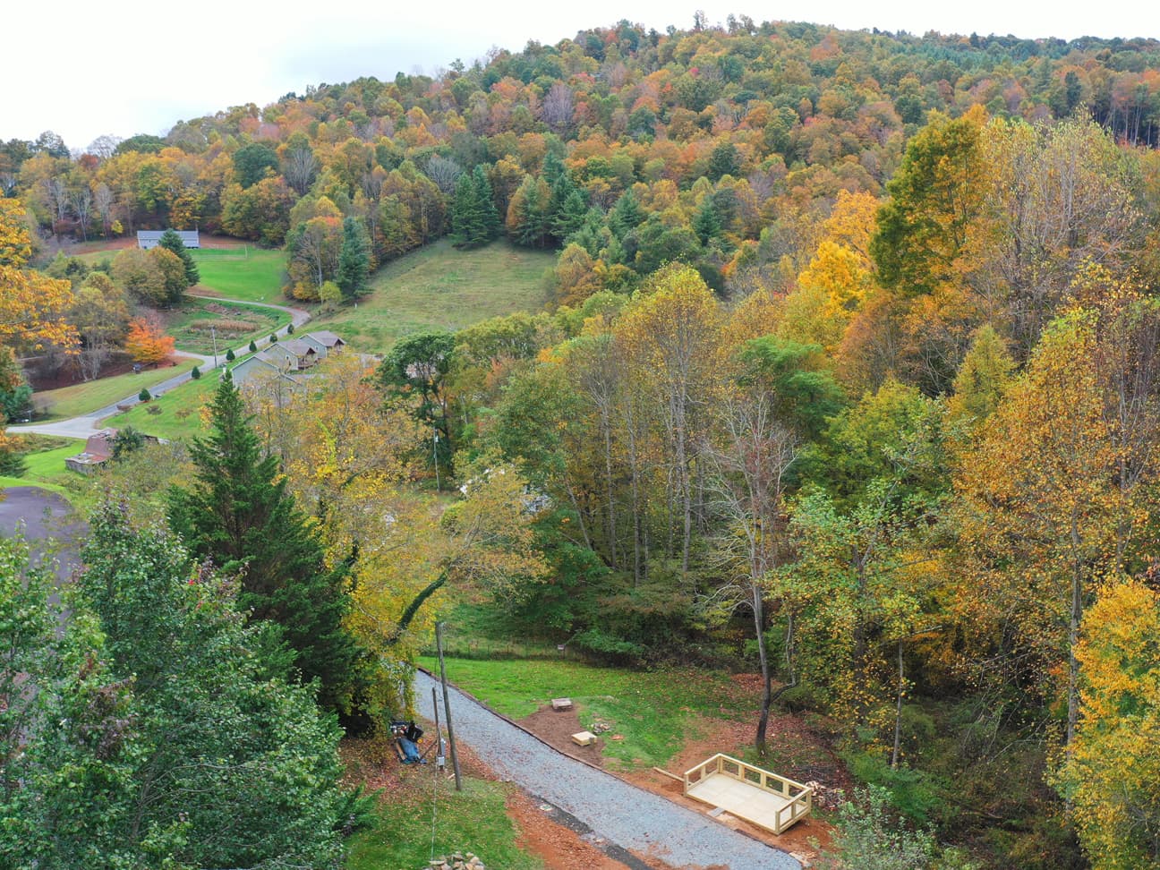 Ariel view of the RV site in autumn, showing a gravel driveway leading to a newly built wooden deck platform.