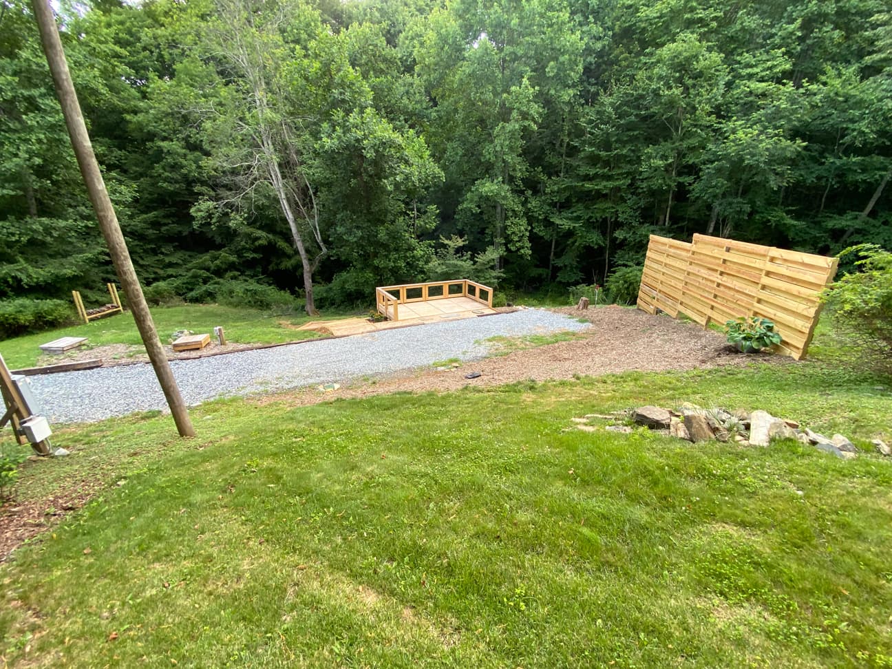 View across the site showing the private deck, gravel path, and privacy fence tucked into the wooded lot